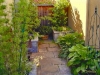 This is a tiny side yard of only about 8' x 10' in size.  Three raised beds define the peaceful retreat, which contains a small shed, a double-seat bench, three focal point plants in the raised beds, and a low bed of shade loving perennials.